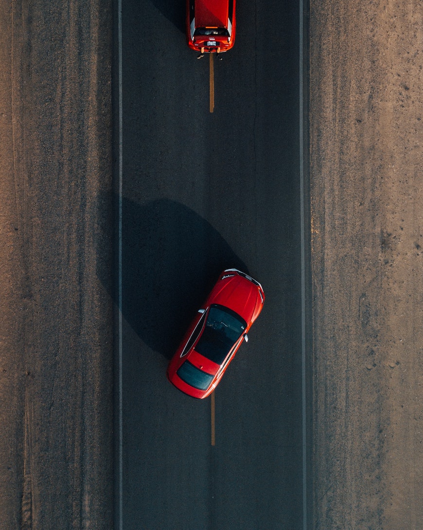 Dwa czerwona samochody na drodze widziane z góry